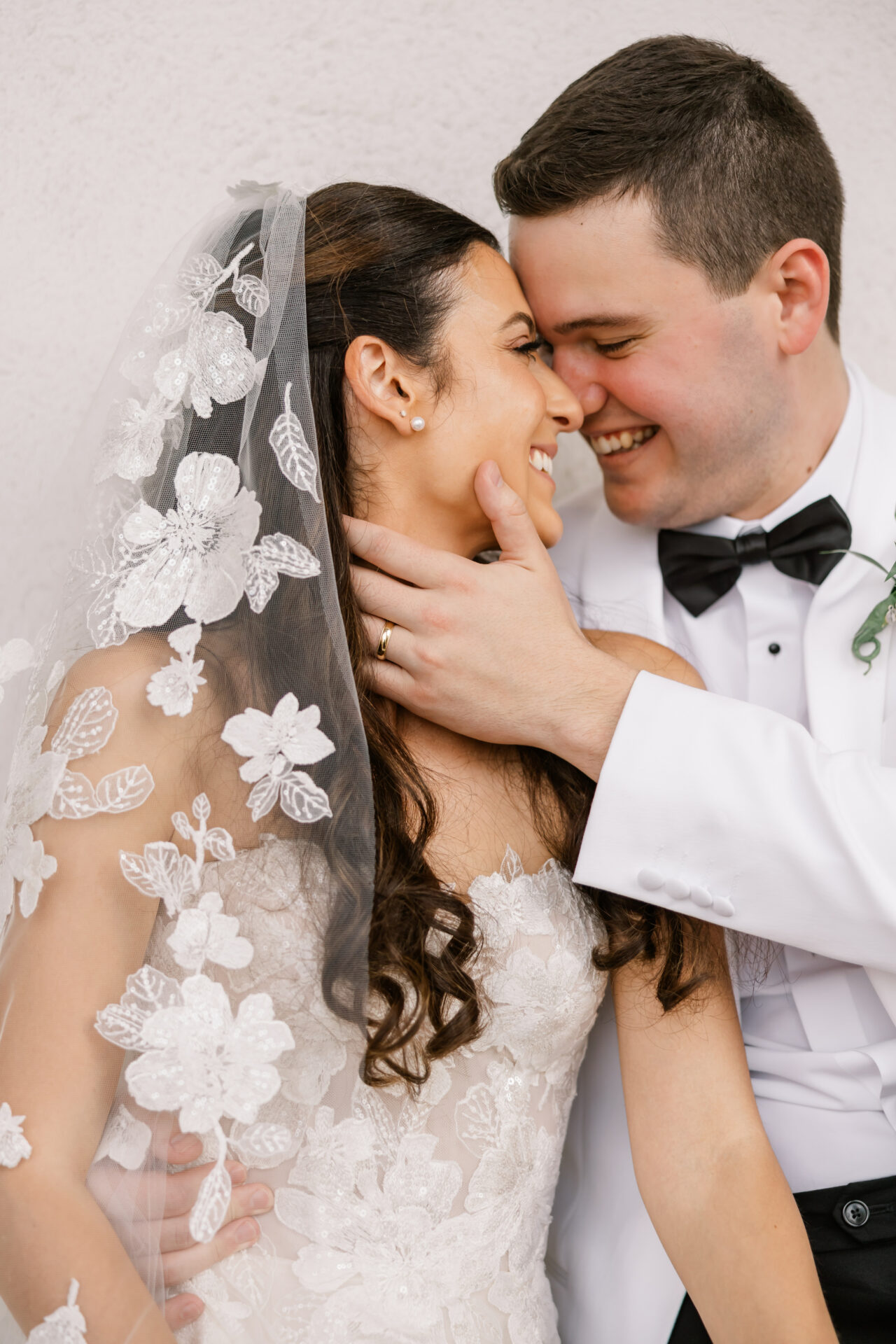 Bride and groom smiling, faces gently touching.