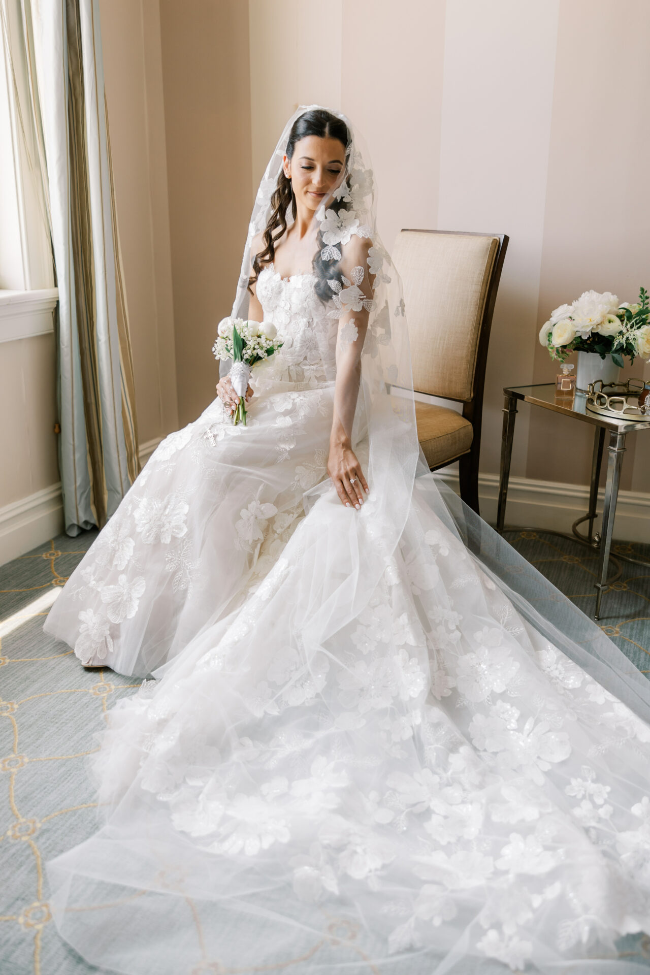 Bride in lace gown, smiling, holding bouquet.