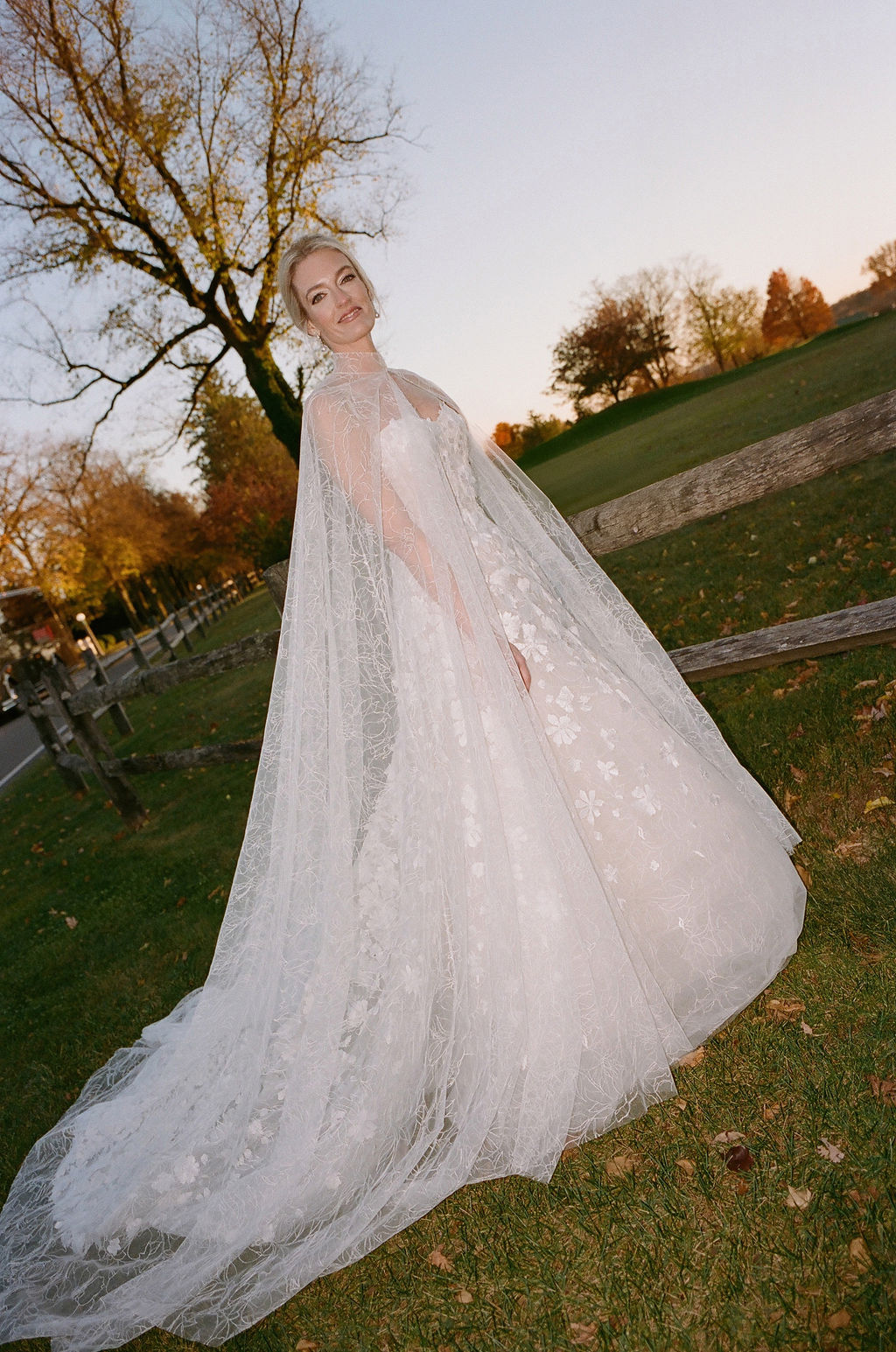 Bride in lace dress outdoors at sunset.