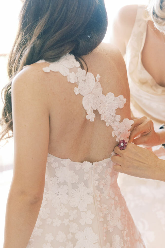 Bride helped into gown by two women.