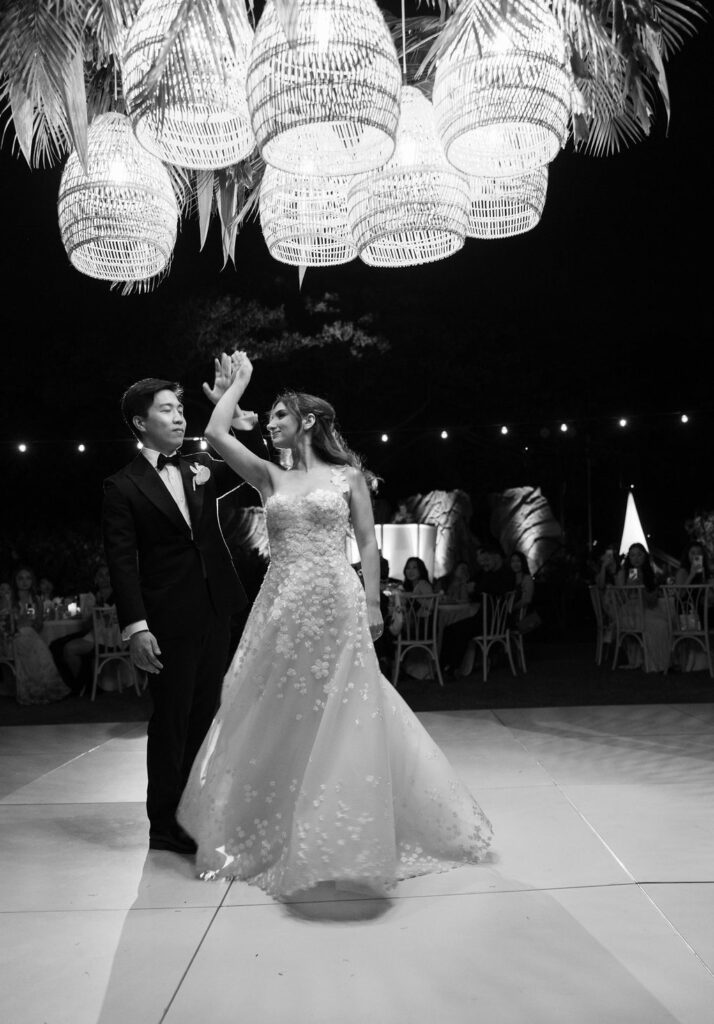 Bride and groom dance under lantern-lit night.