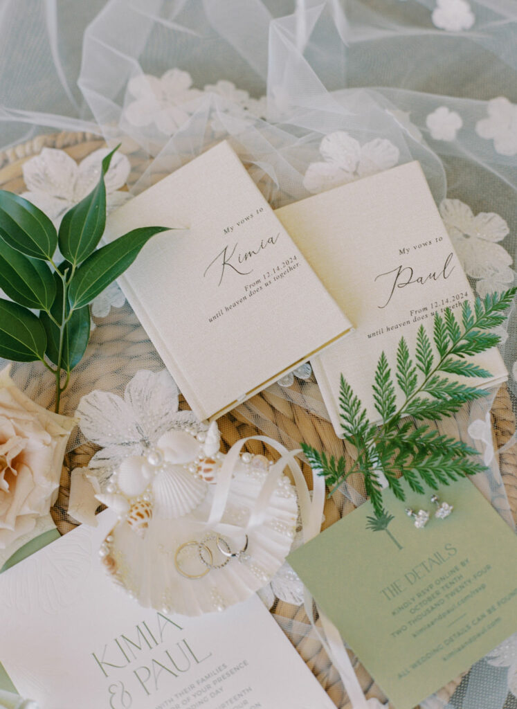 Wedding stationery, rings, flowers on woven mat.