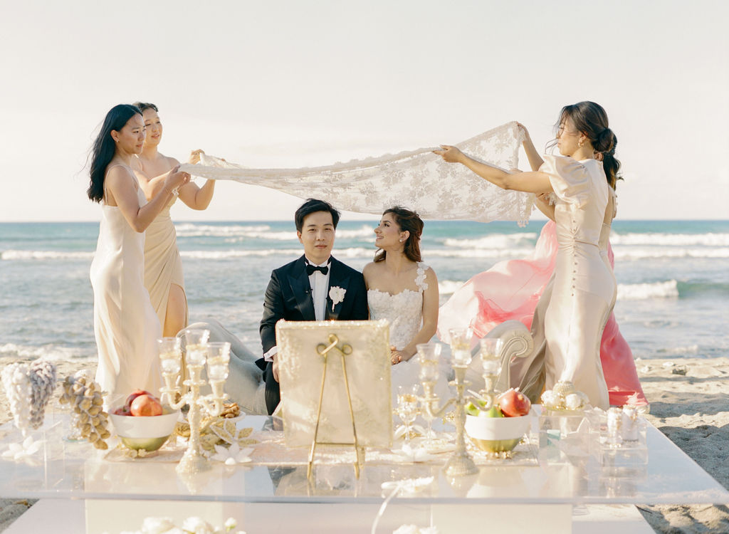 Bride, groom, and friends at elegant beach wedding.