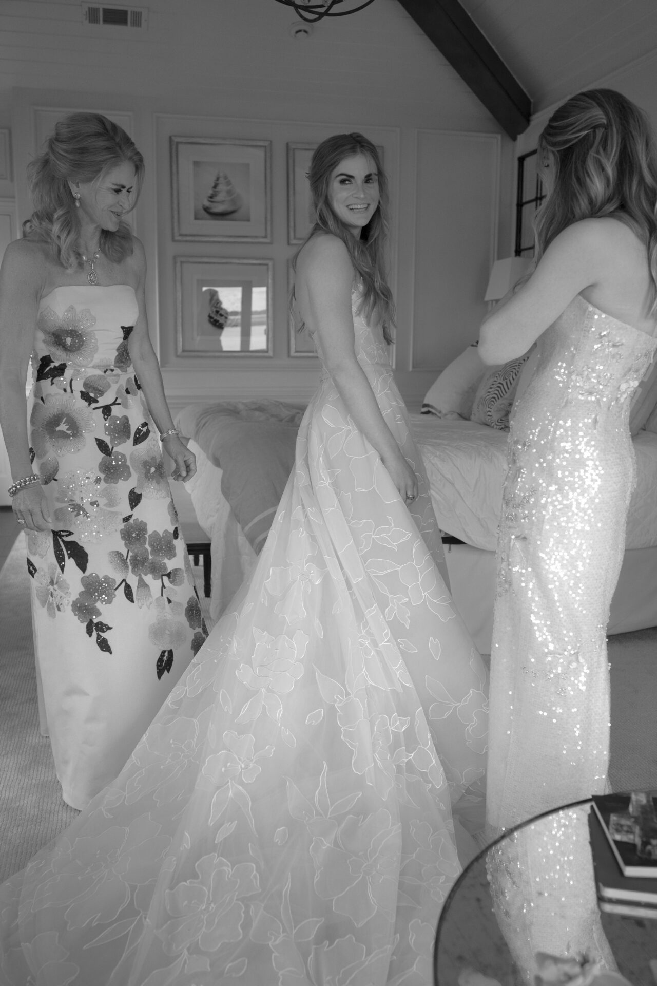 Bride in floral gown with bridesmaids, smiling.