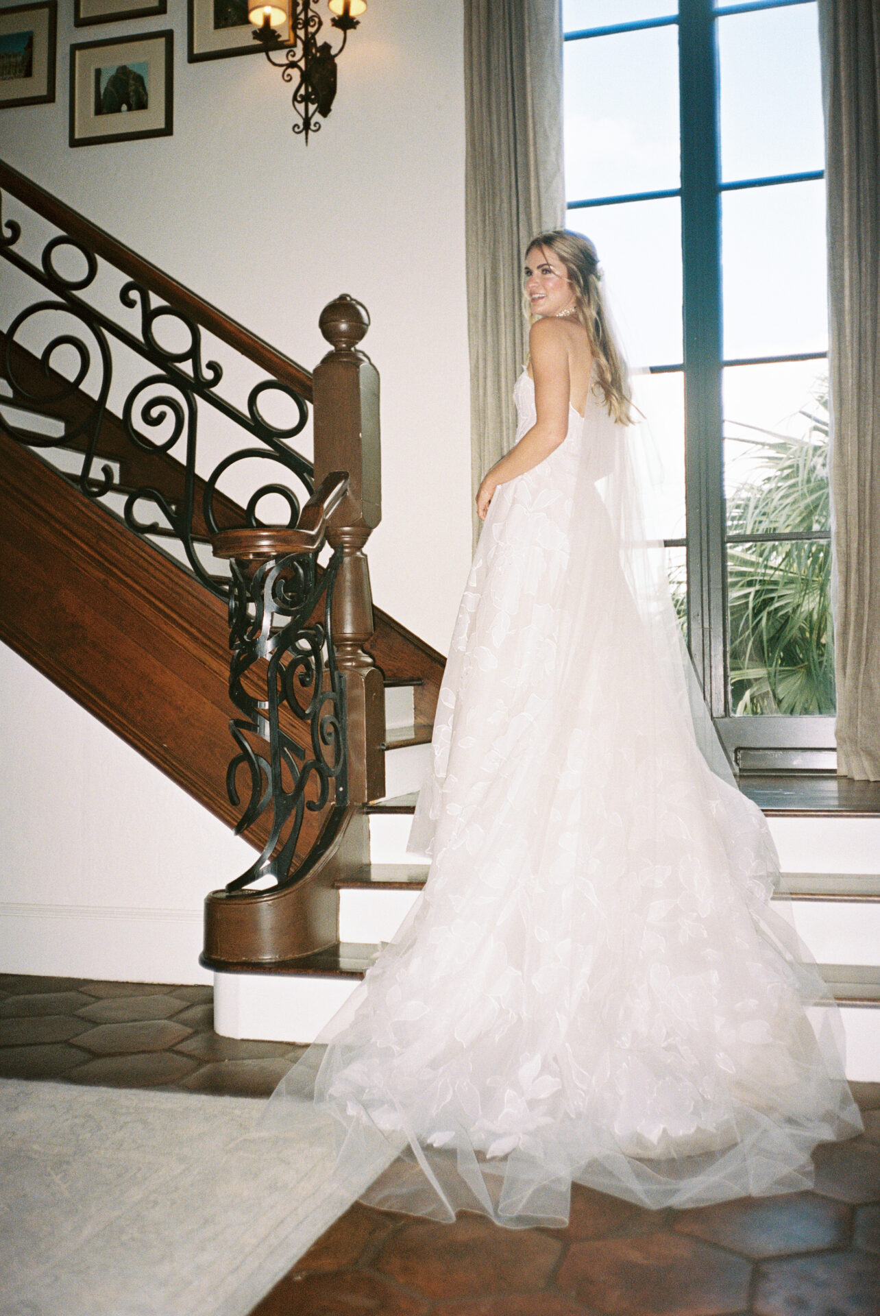 Bride on staircase, looking over shoulder.