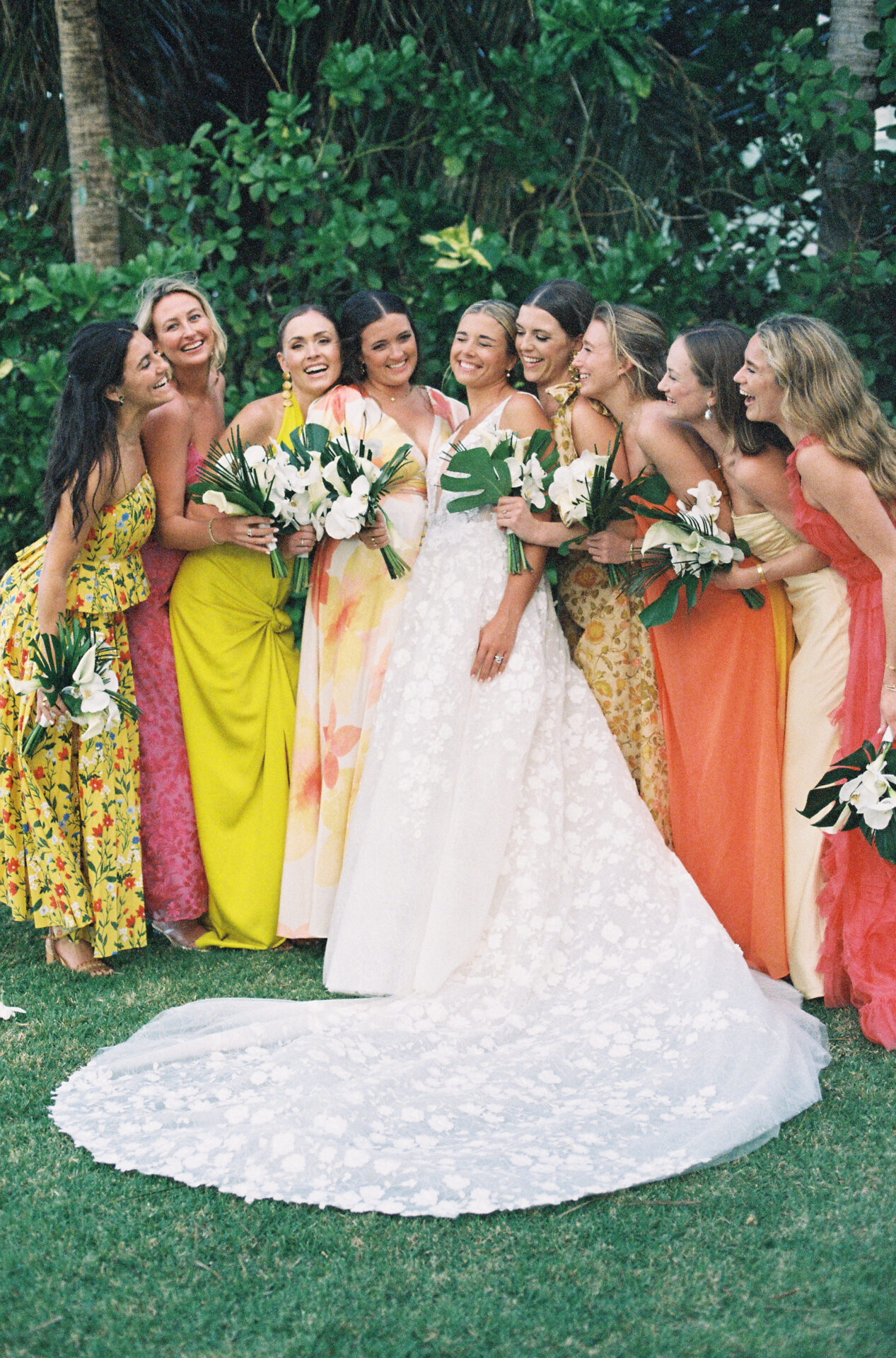 Bride with eight bridesmaids smiling outdoors.
