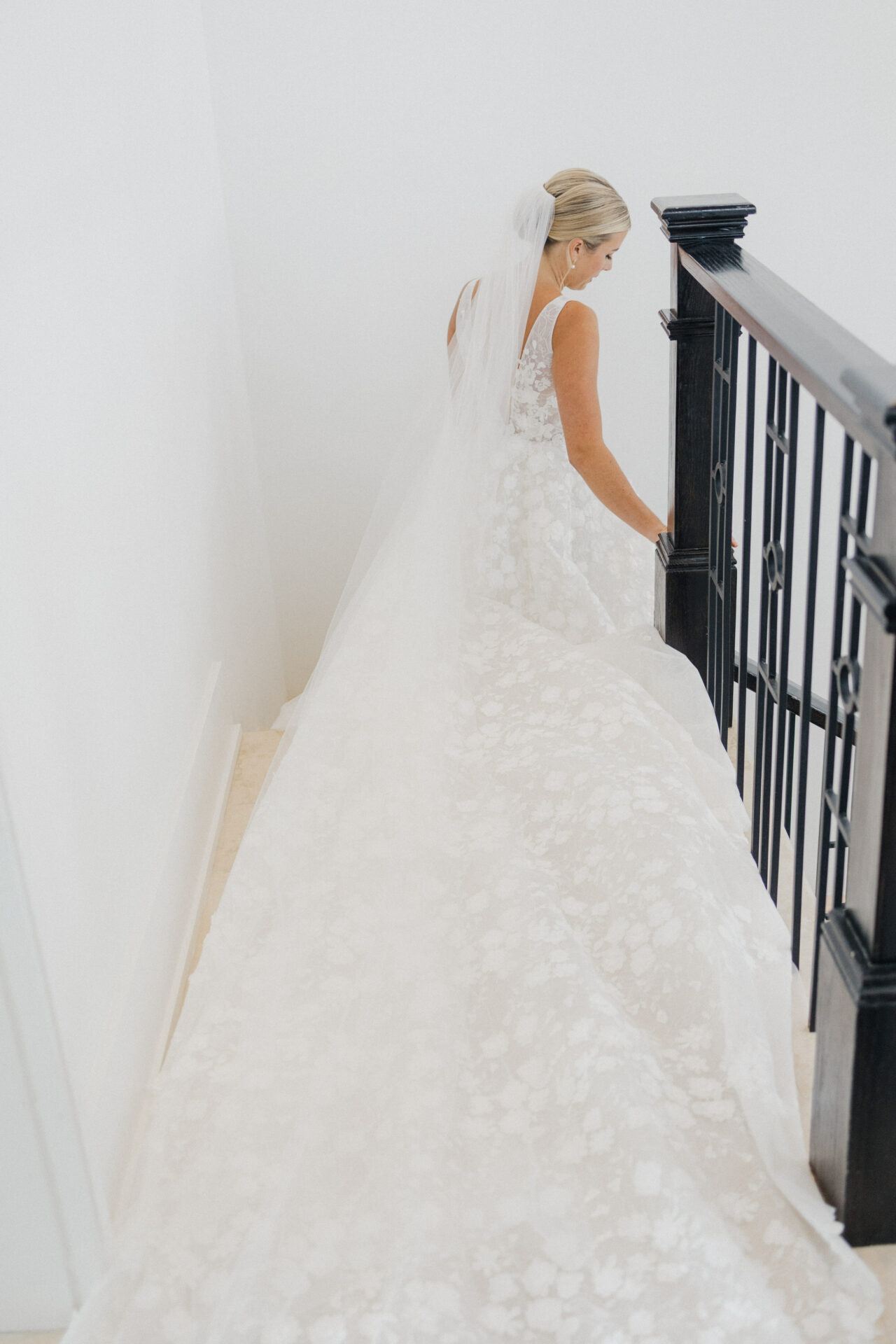Bride in lace gown descends staircase.