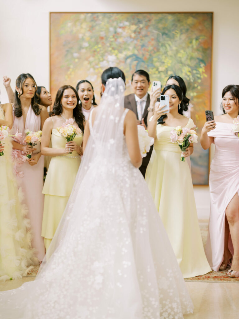 Bride Katya Ruiz in gown, bridesmaids celebrate indoors.