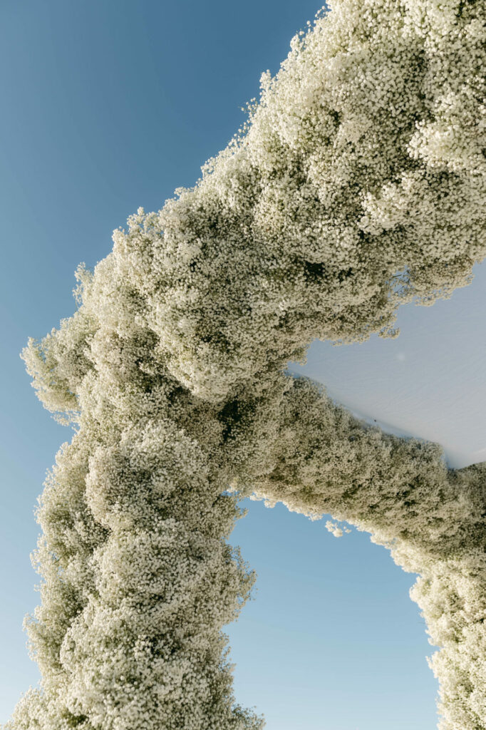 White floral arch against clear blue sky.