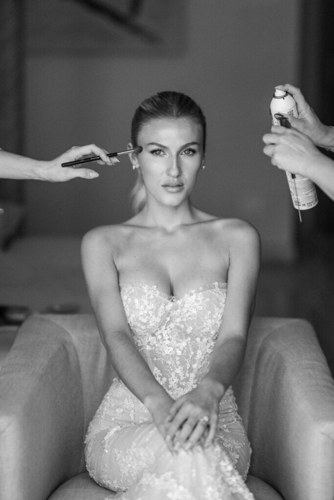 Woman in lace gown gets makeup and hairstyling.