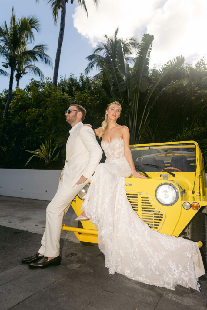 Bride and groom by yellow vintage car.
