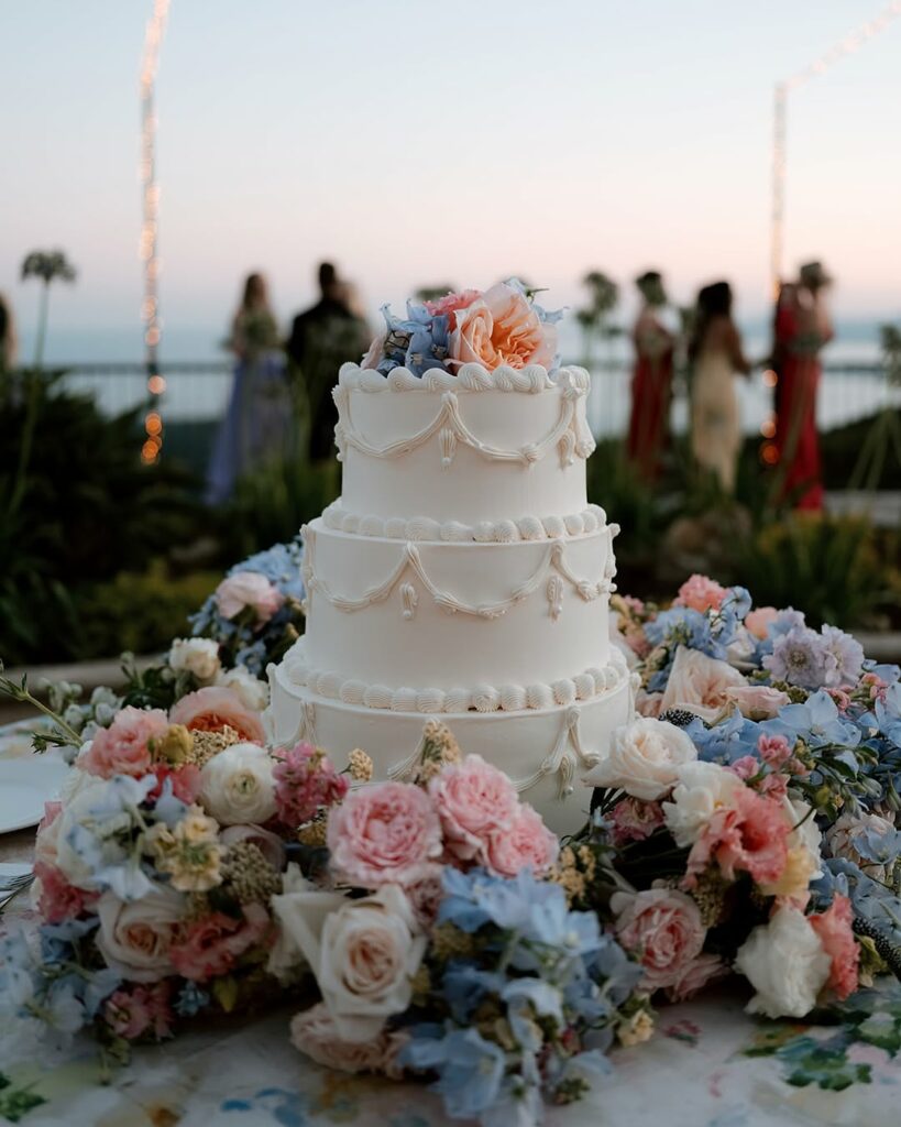 White wedding cake with pastel flowers, outdoors.