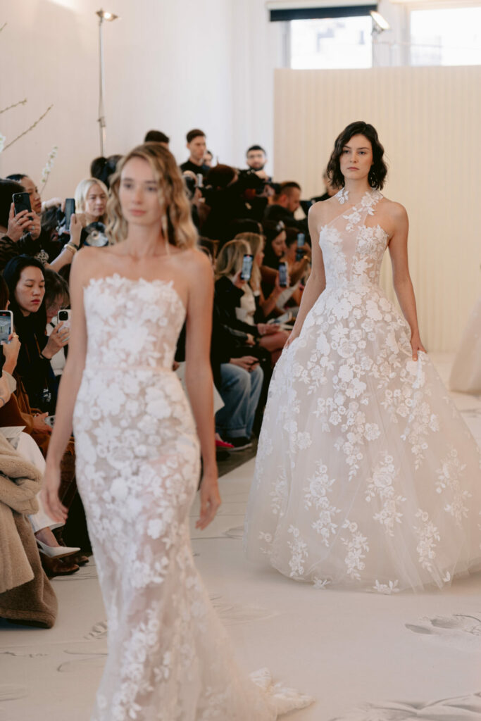 Two models in lace gowns on runway.