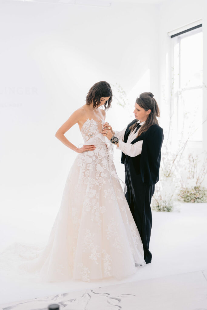 Brides dress adjusted in bright room.