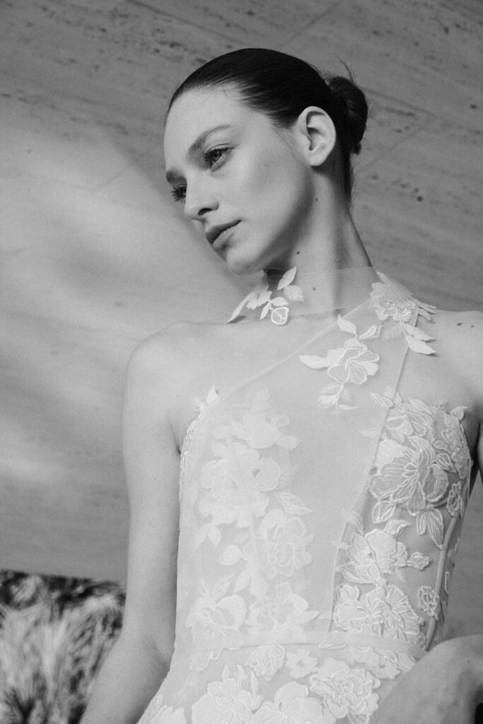 Woman in lace dress, looking down, grayscale.