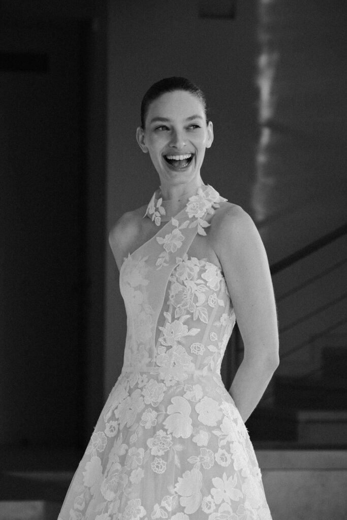 Smiling woman in floral one-shoulder gown.