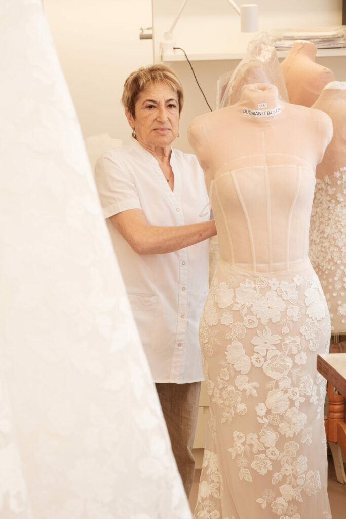 Woman beside dress form with lace gown.