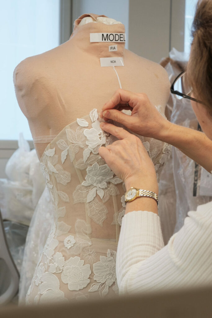 Person pins lace fabric onto dress form.