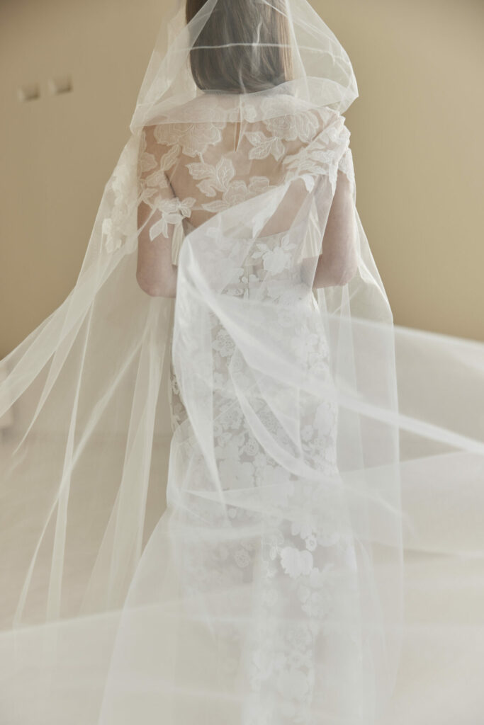 Bride in lace gown with flowing veil.