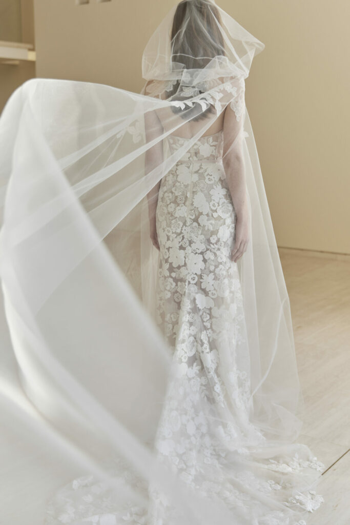 Bride in lace gown with flowing veil.