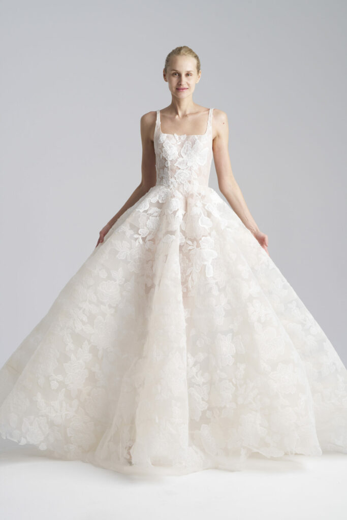 Woman in white lace bridal gown posing gracefully.