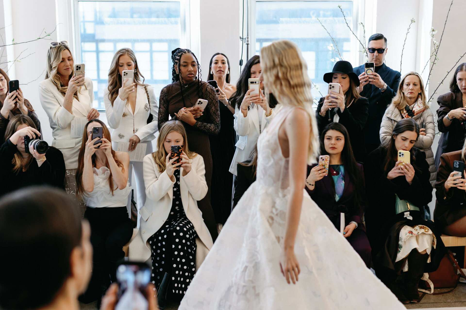 Model in white gown walks indoor runway.