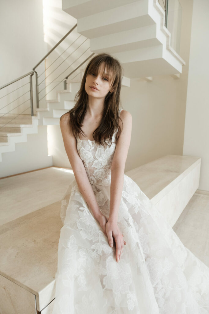 Woman in lace white dress on stone ledge.