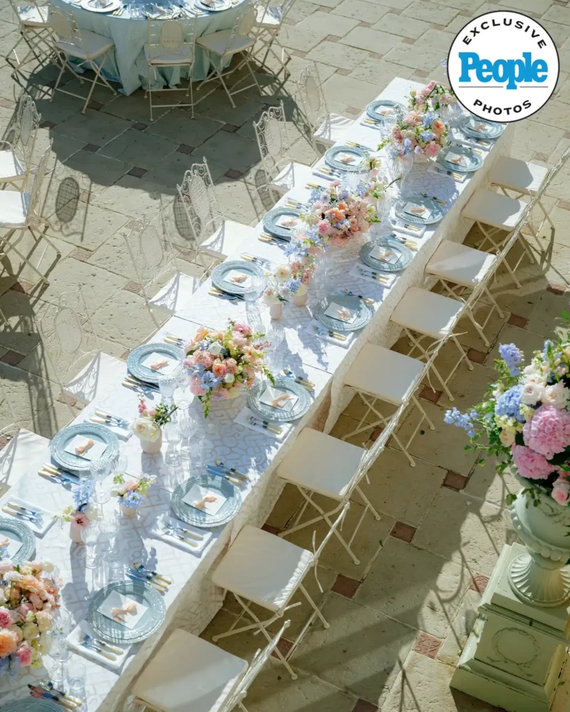 Elegant outdoor table with pastel flowers, sunlight.