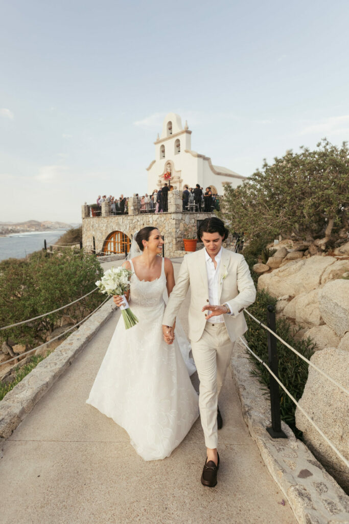 Bride and groom walk outside church, smiling.
