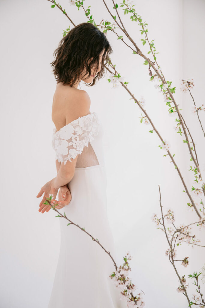 Woman in white dress among blooming branches.