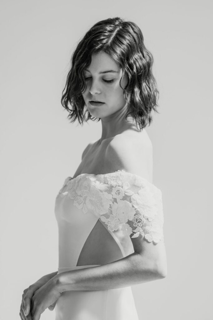 Woman in lace dress looks down calmly.