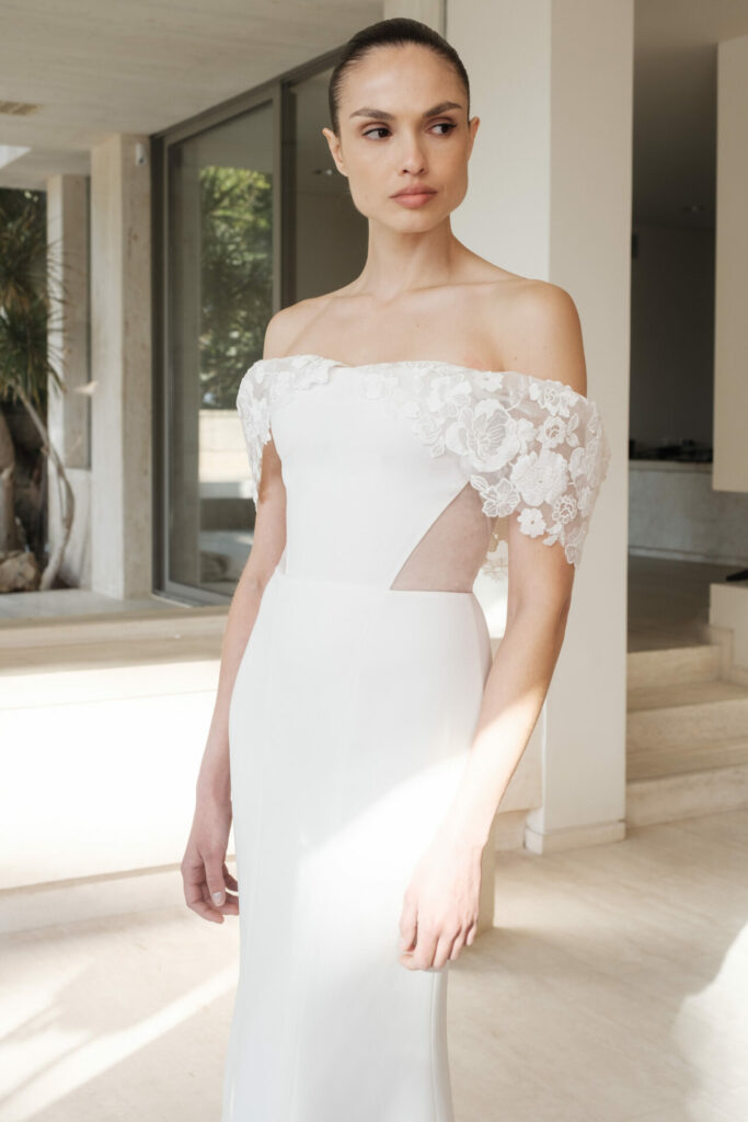 Woman in white lace dress by windows.
