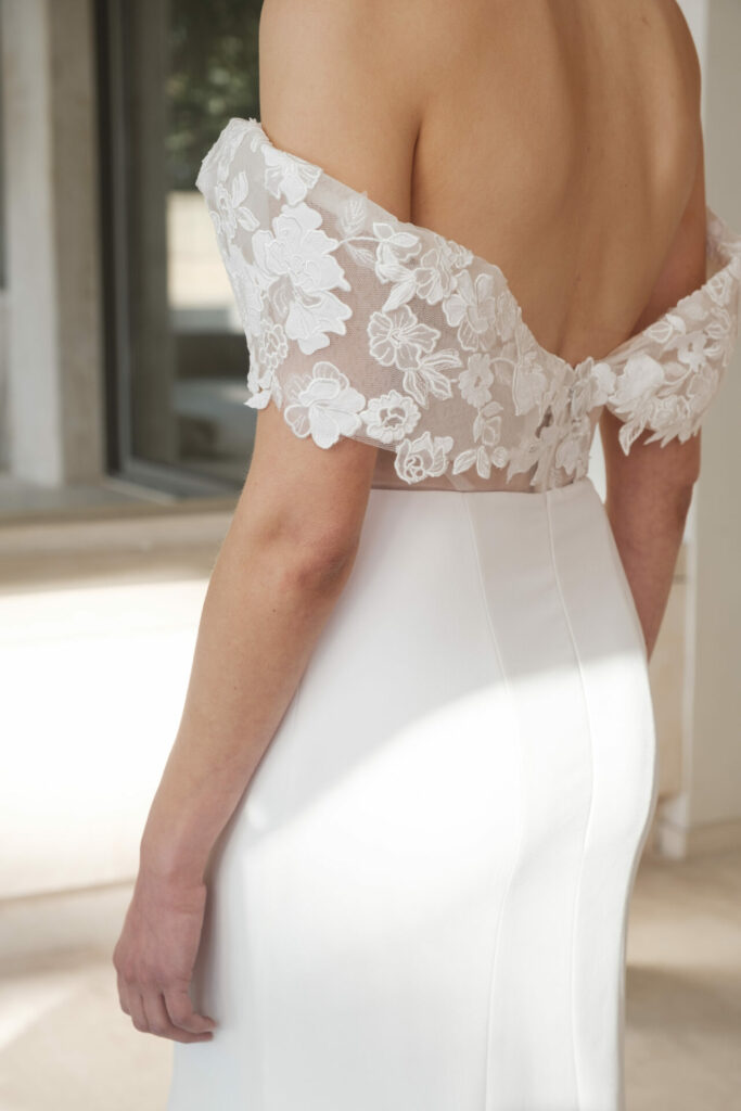 Bride in lace wedding dress by window.
