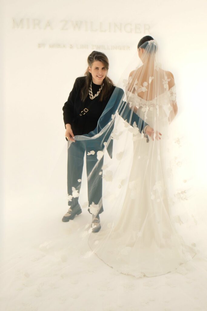 Woman adjusts bride’s floral, sheer veil.