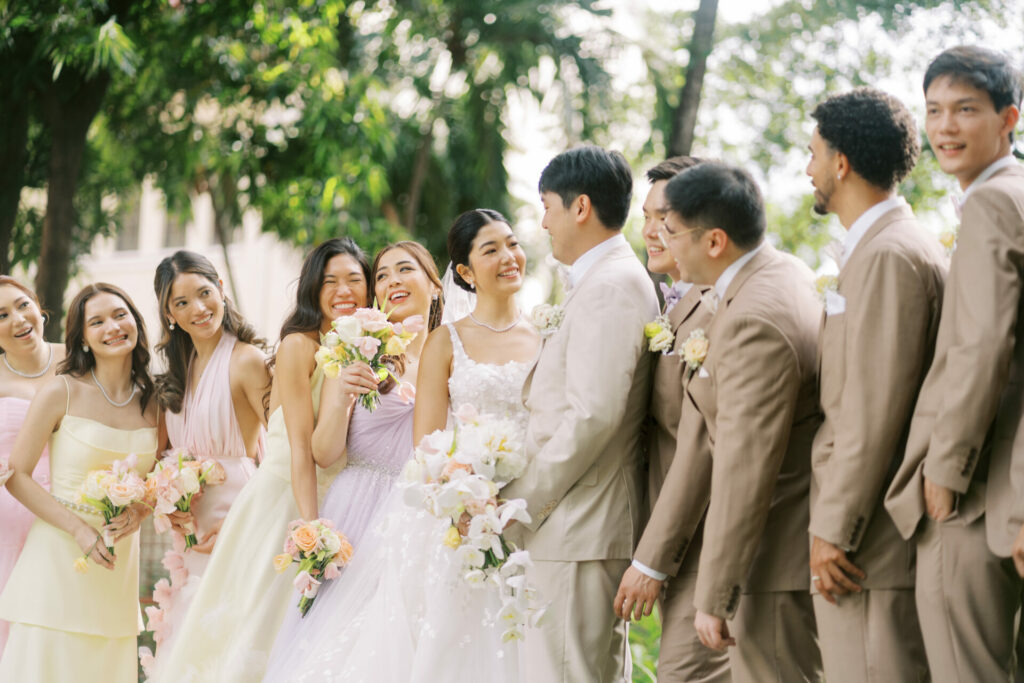 Bride and groom smiling, surrounded by wedding party.
