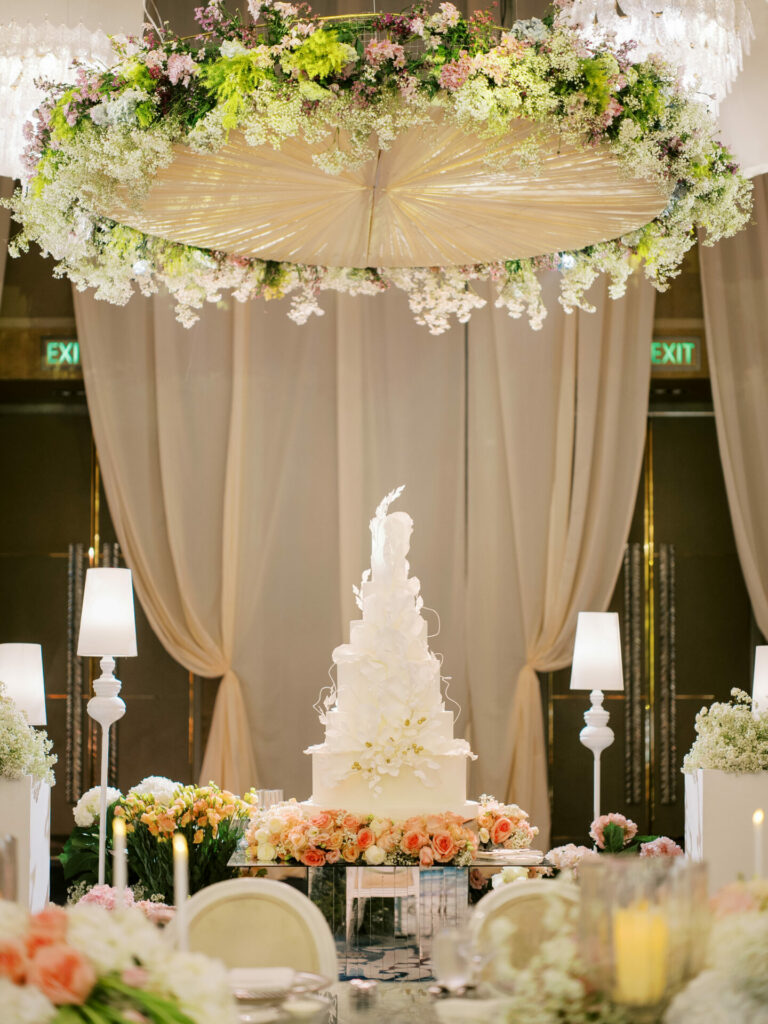 Tall white wedding cake on floral table.