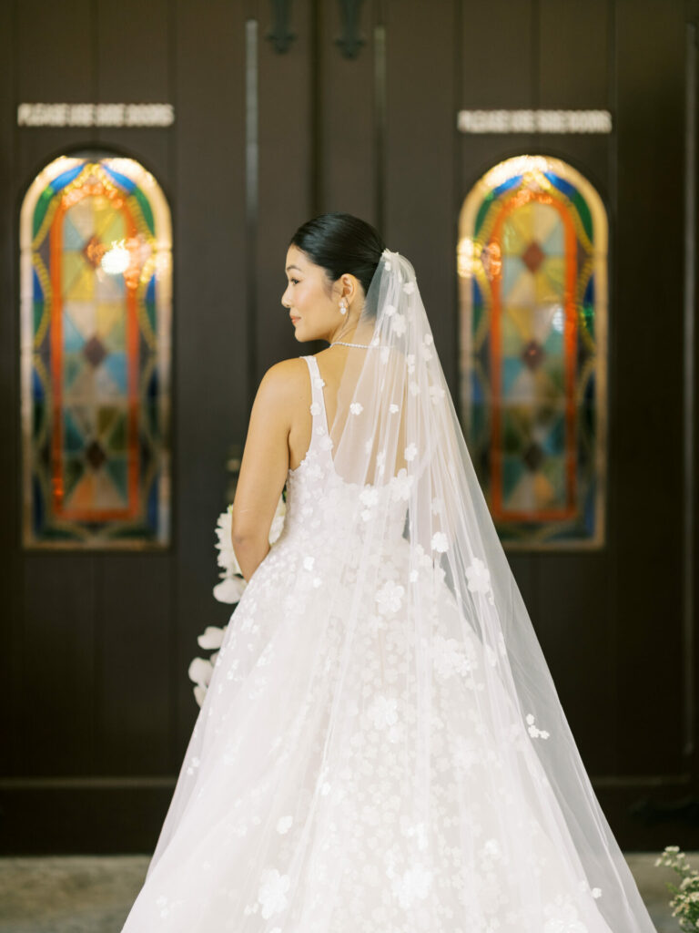 Bride Katya Ruiz in lace gown by doors.