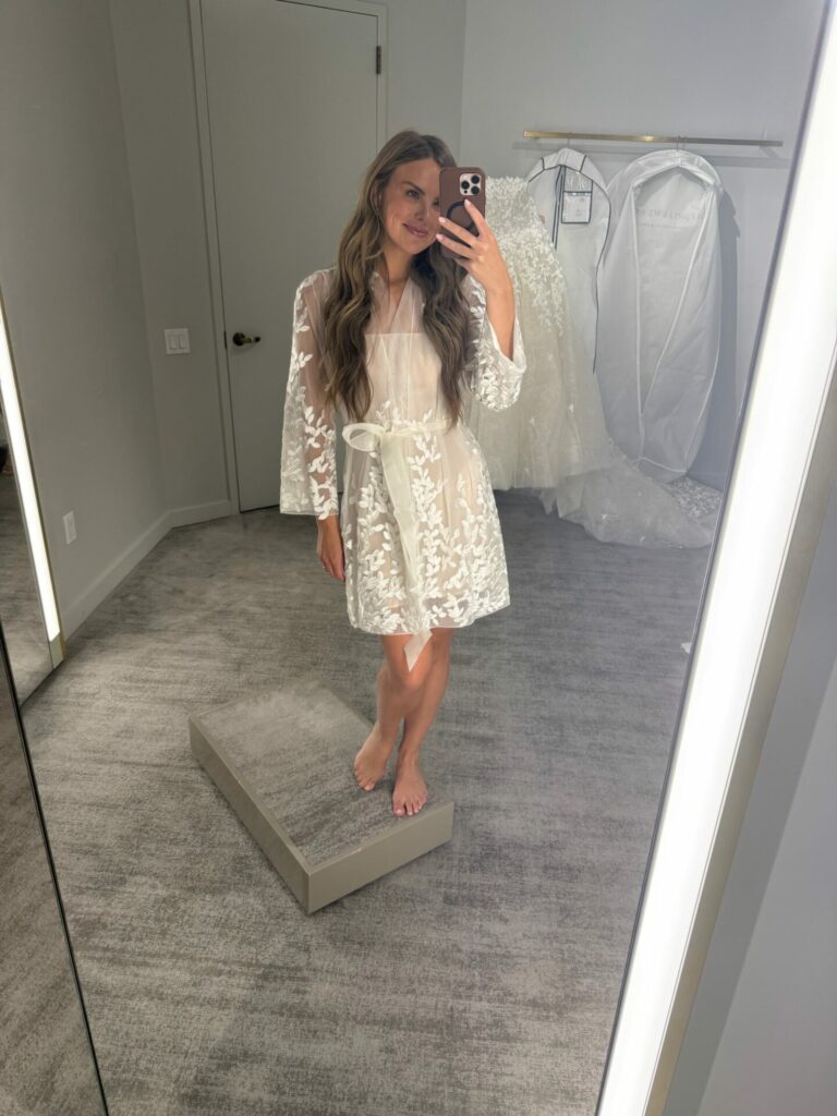 Woman in sheer robe takes mirror selfie.