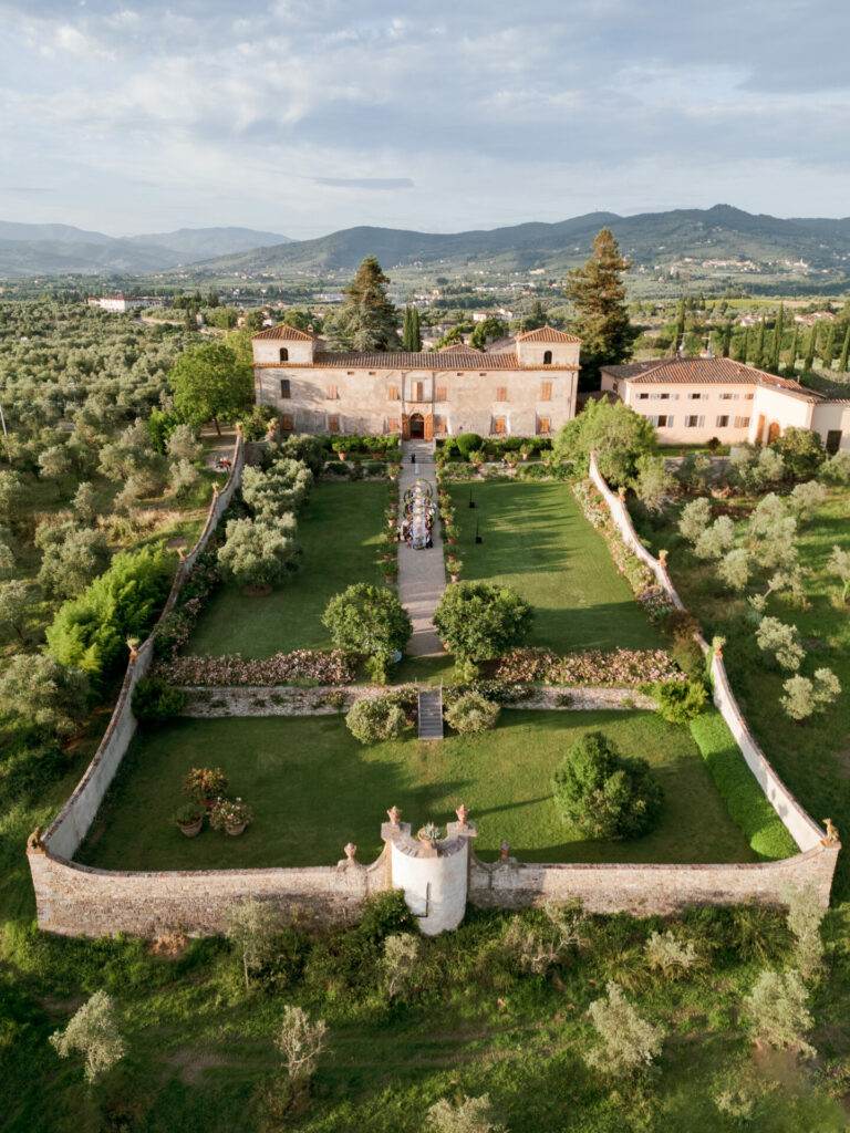 Aerial of villa gardens, guests at outdoor event.