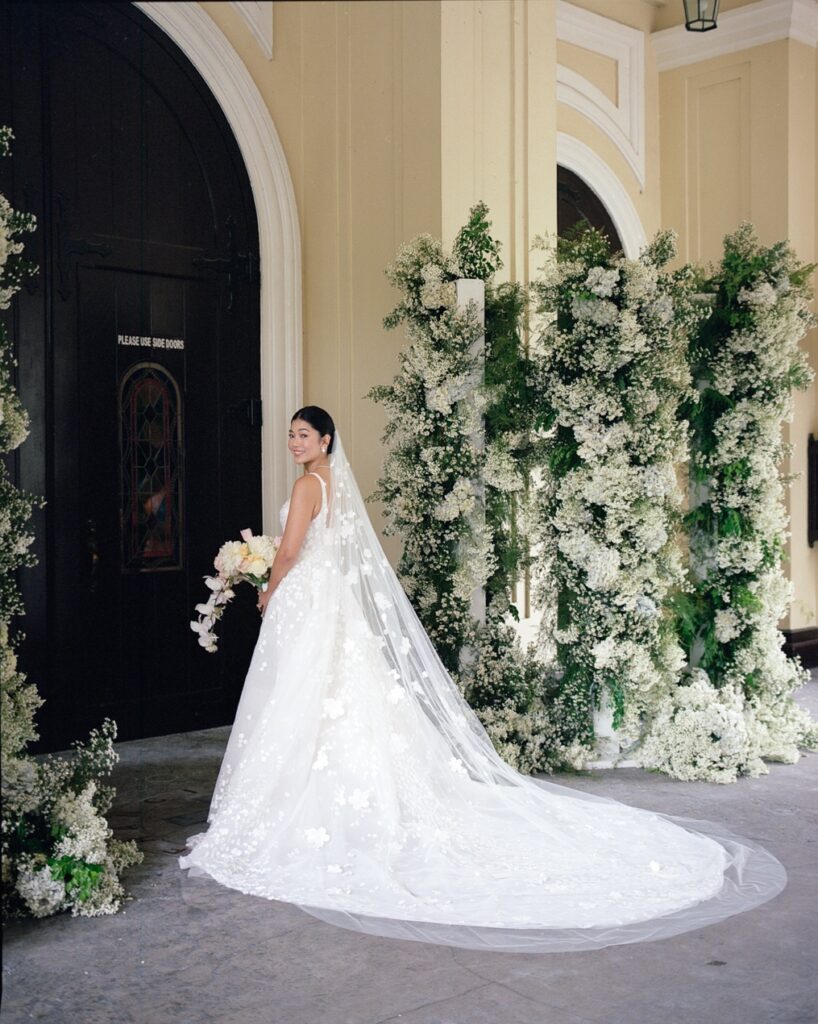 Bride in Amy gown poses with bouquet, veil.