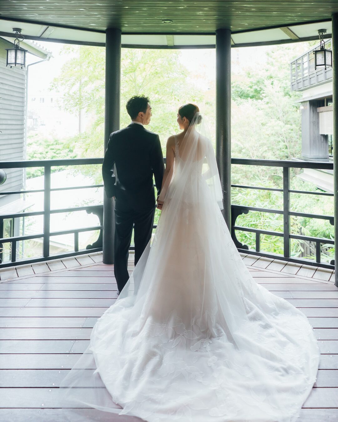 Bride and groom on balcony, facing away.