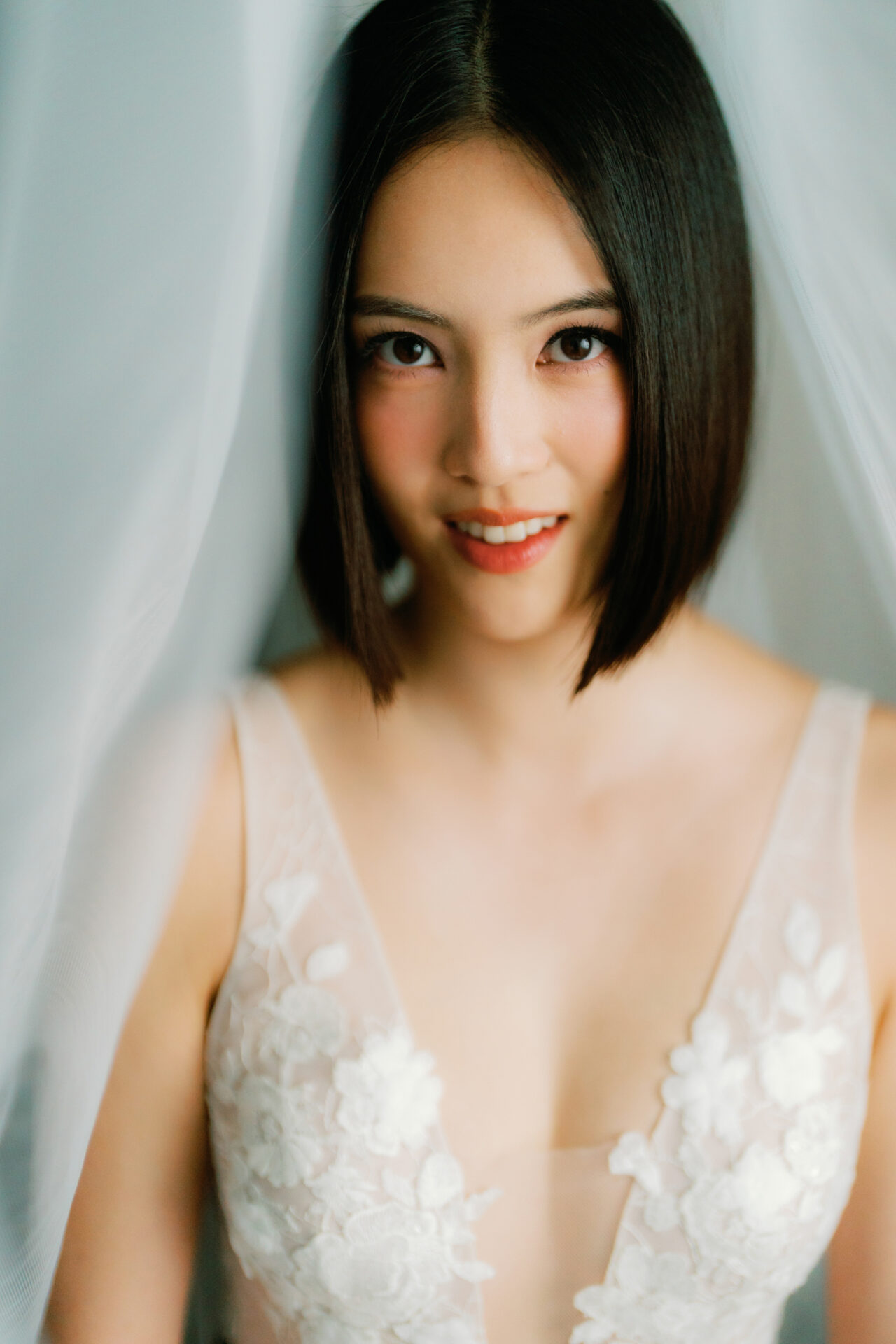 Smiling woman in sheer, floral dress and veil.