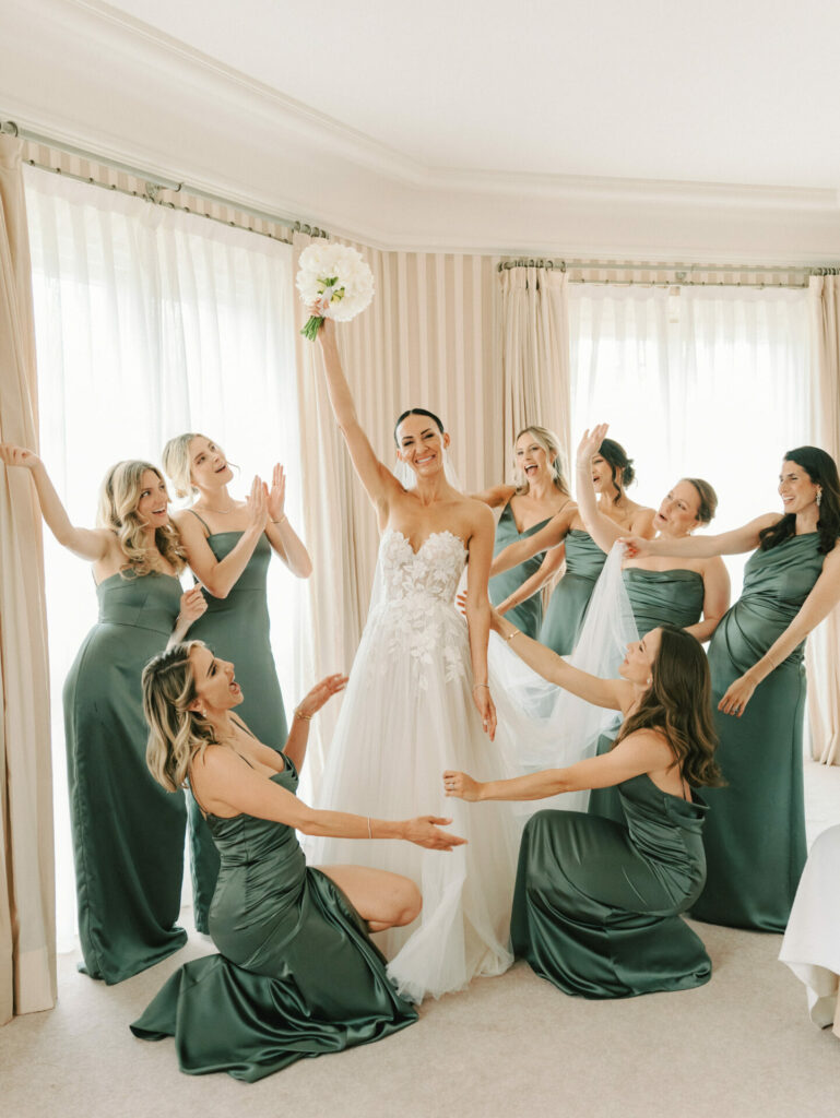Bride with bouquet and bridesmaids in sage green, smiling.