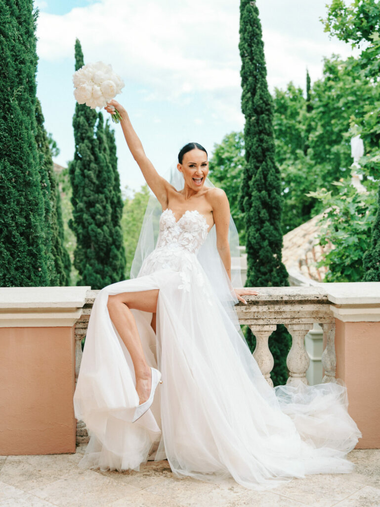 Katya Ruiz in luxe white gown, smiling with bouquet.