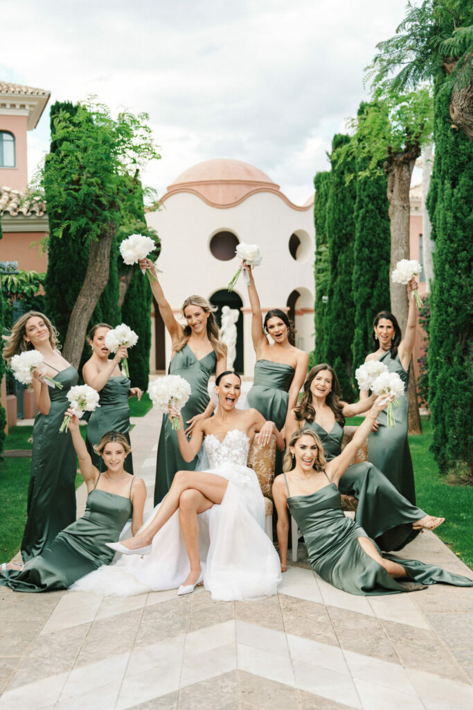 Bride in couture gown with bridesmaids in garden.