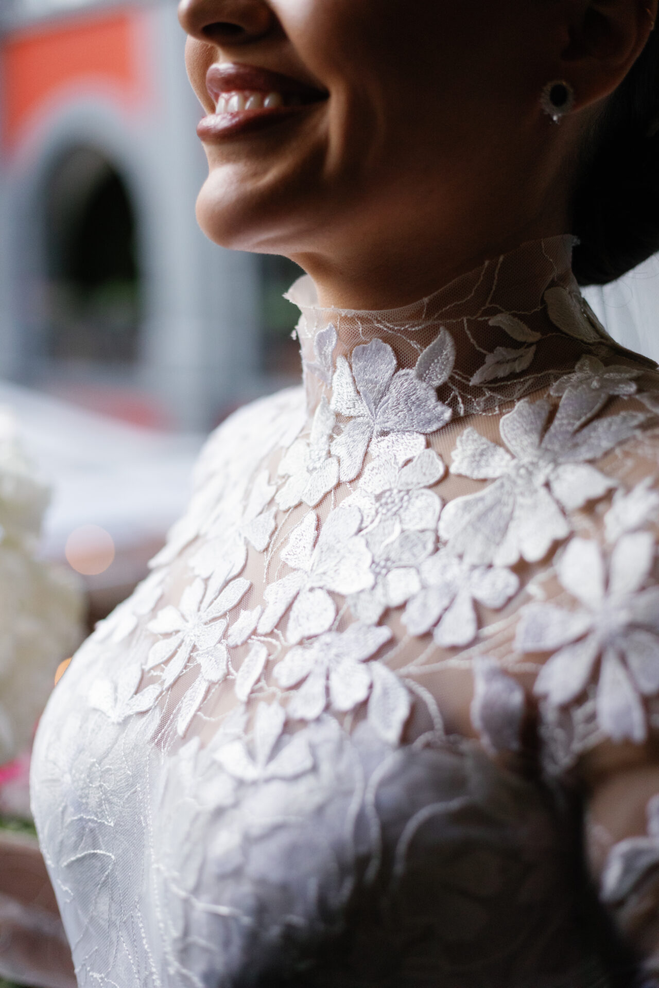 Woman smiling in sheer floral lace wedding dress.