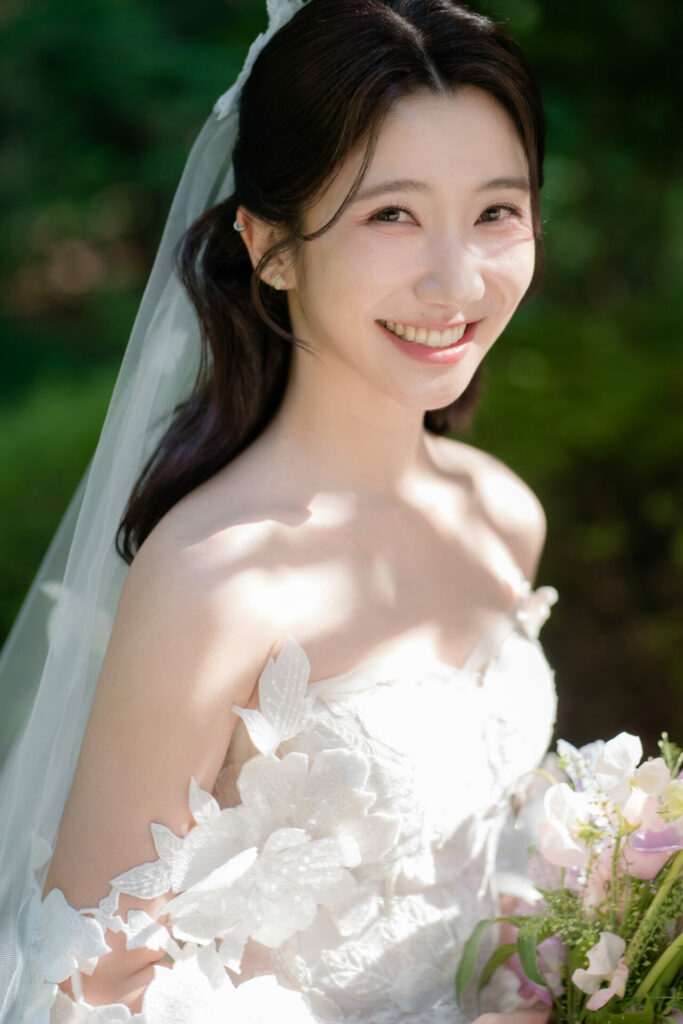 Bride smiles outdoors in Mira Zwillinger gown.