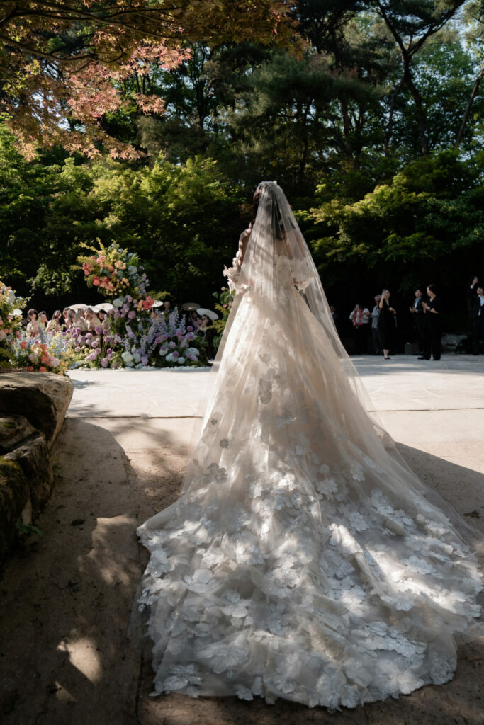 Bride Katya Ruiz in gown, sunlit garden.