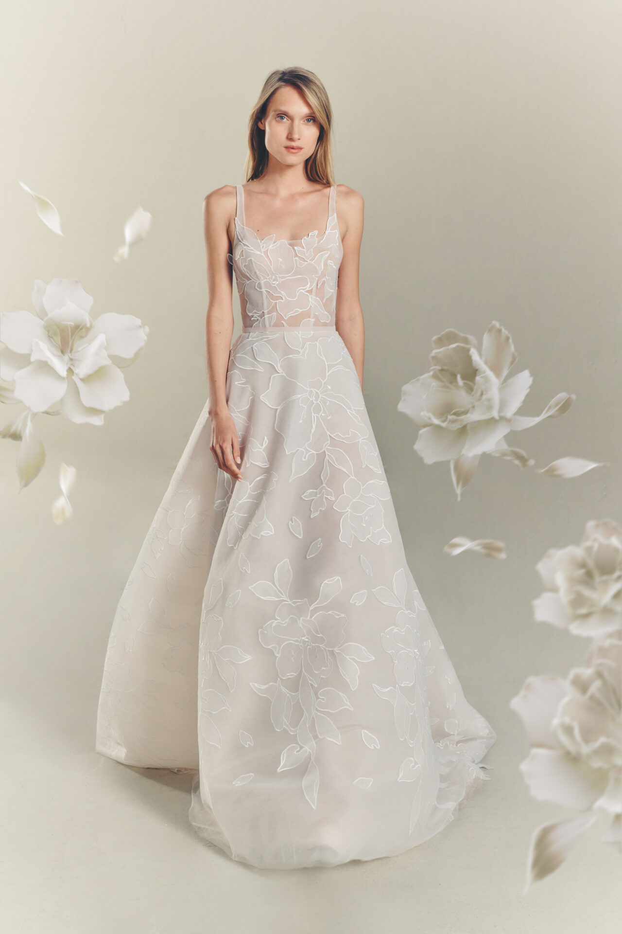 Woman in floral white gown, floating flowers surrounding.