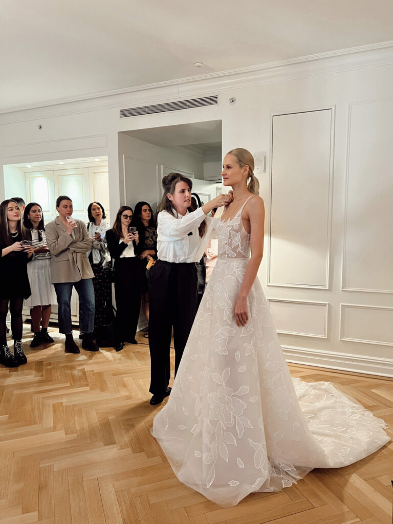 Bride’s dress adjusted as guests watch nearby.
